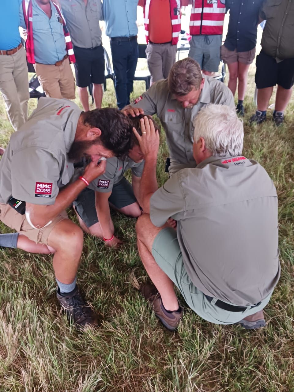 Men praying over a brother on the field
